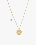 Gold compass necklace with a round pendant on a light grey background
