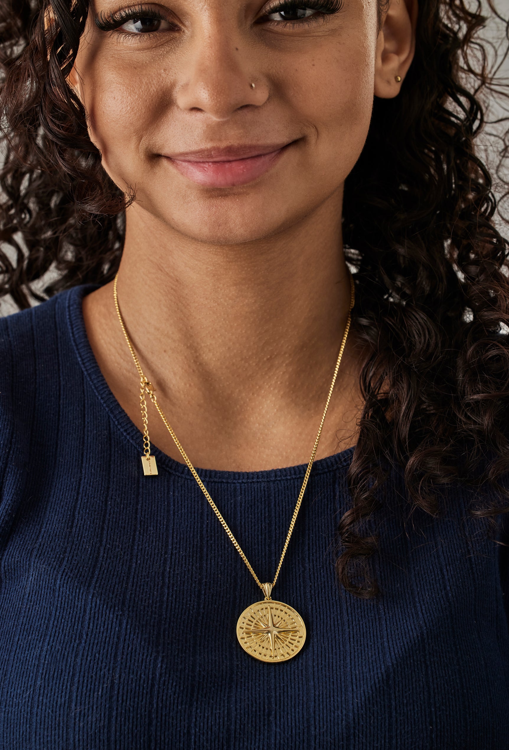 Woman wearing a gold necklace with a pendant