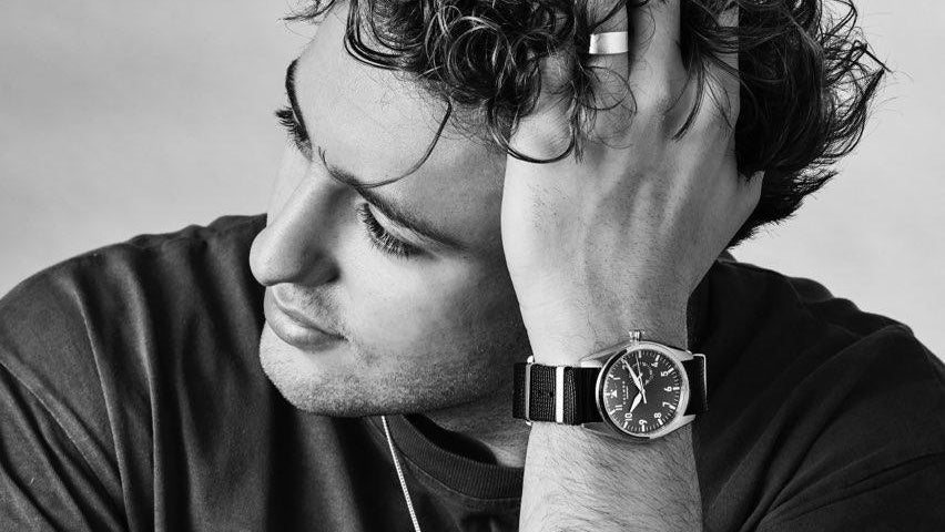 Man wearing a watch with a neutral background