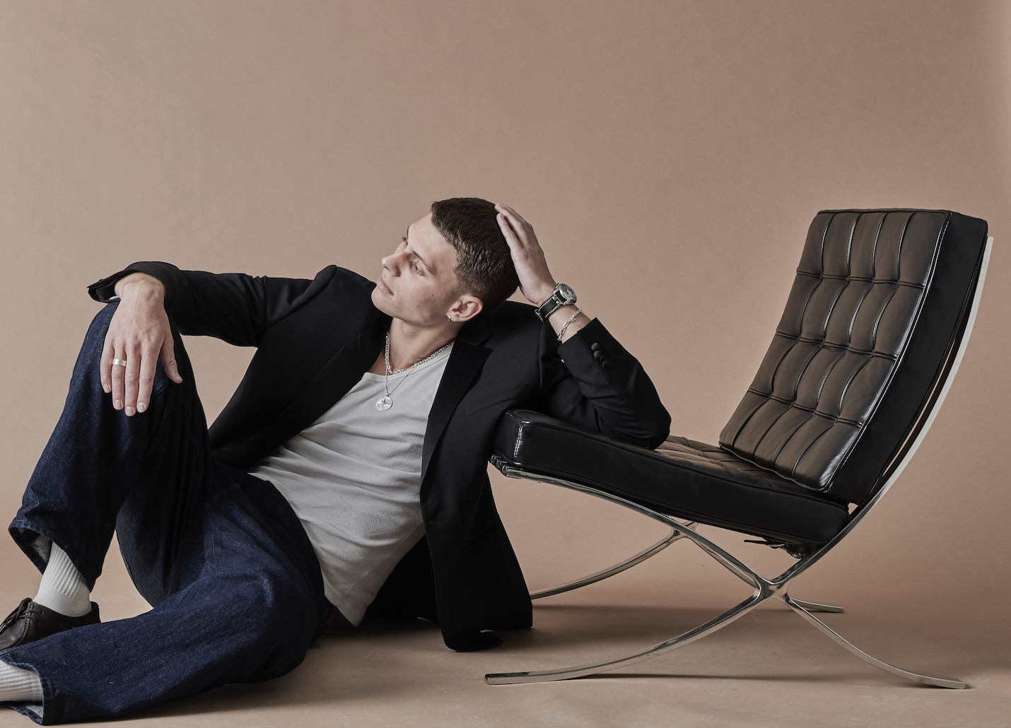 Man sitting on a modern chair against a beige background