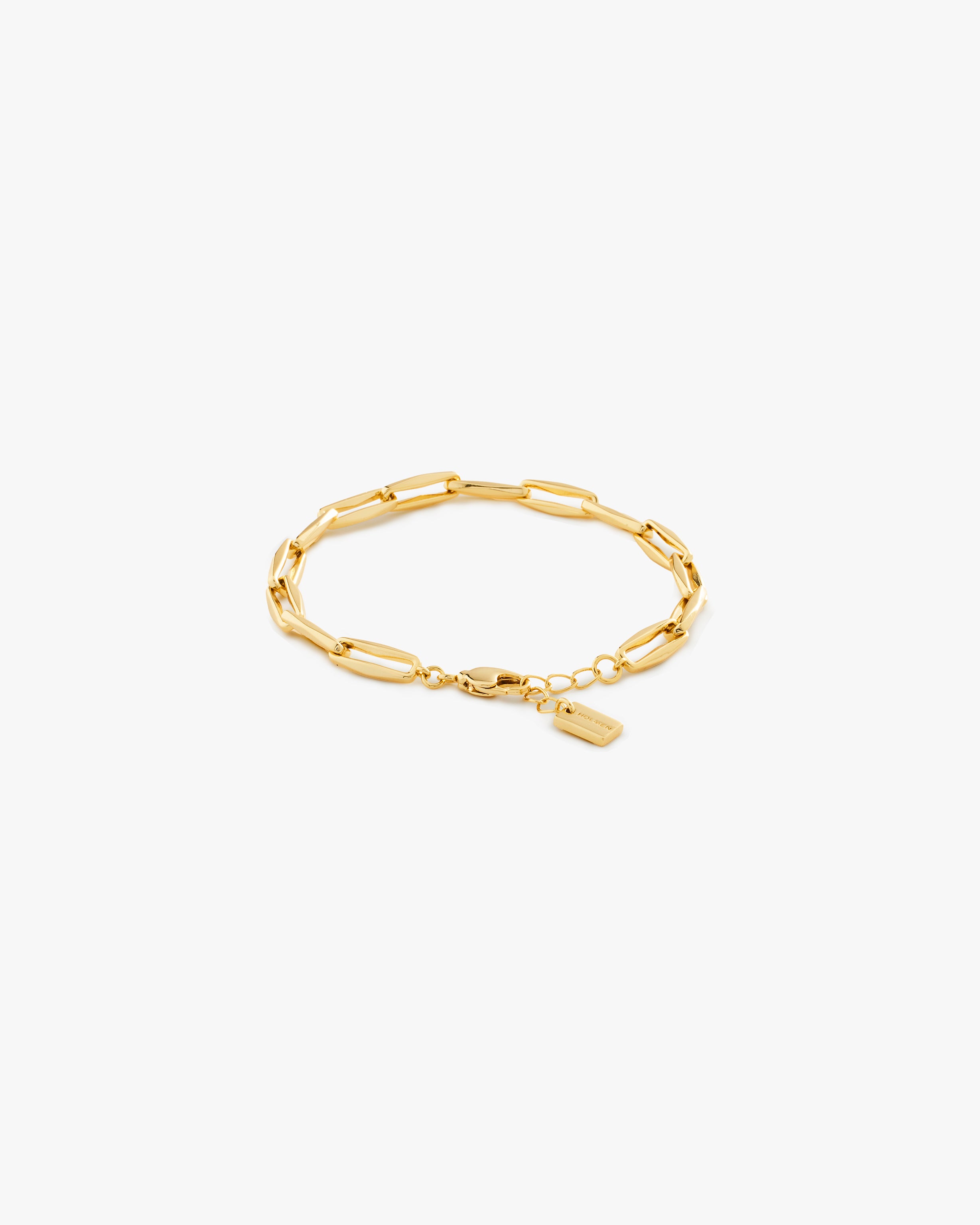 Gold bracelet with a tag on a light grey background