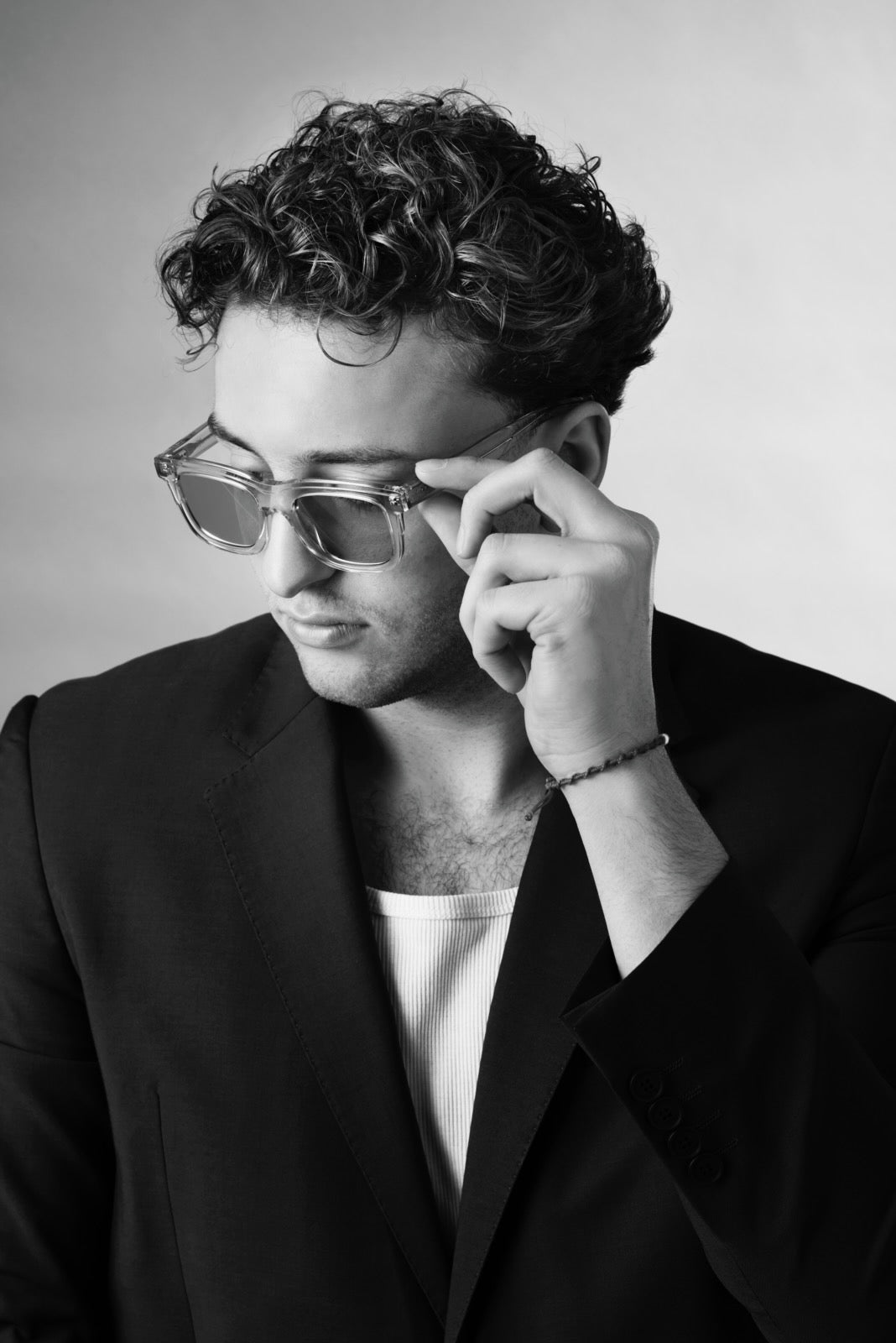 Person wearing glasses and a black blazer against a plain background