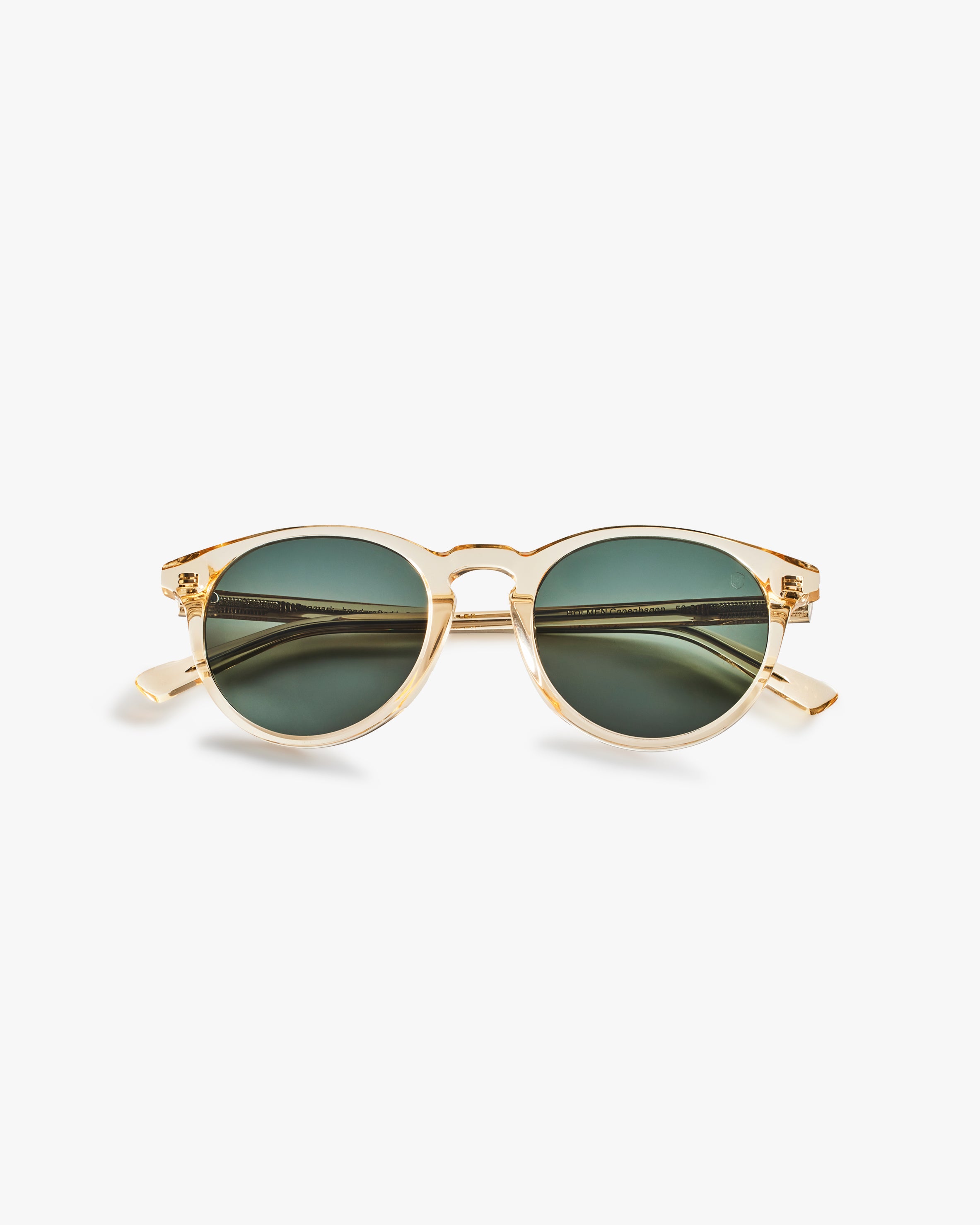 Gold-framed sunglasses with green lenses on a light grey background