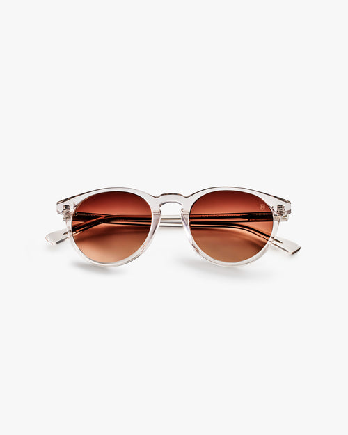 Sunglasses with brown lenses and gold frame on a light grey background