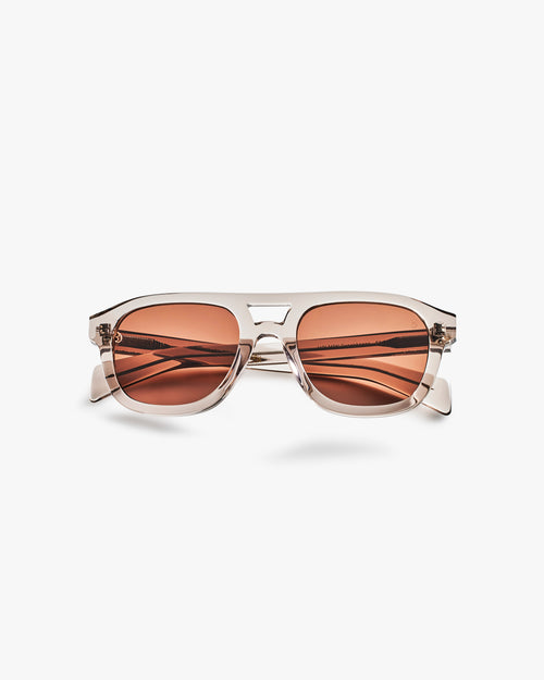 Sunglasses with brown lenses and clear frame on a light grey background