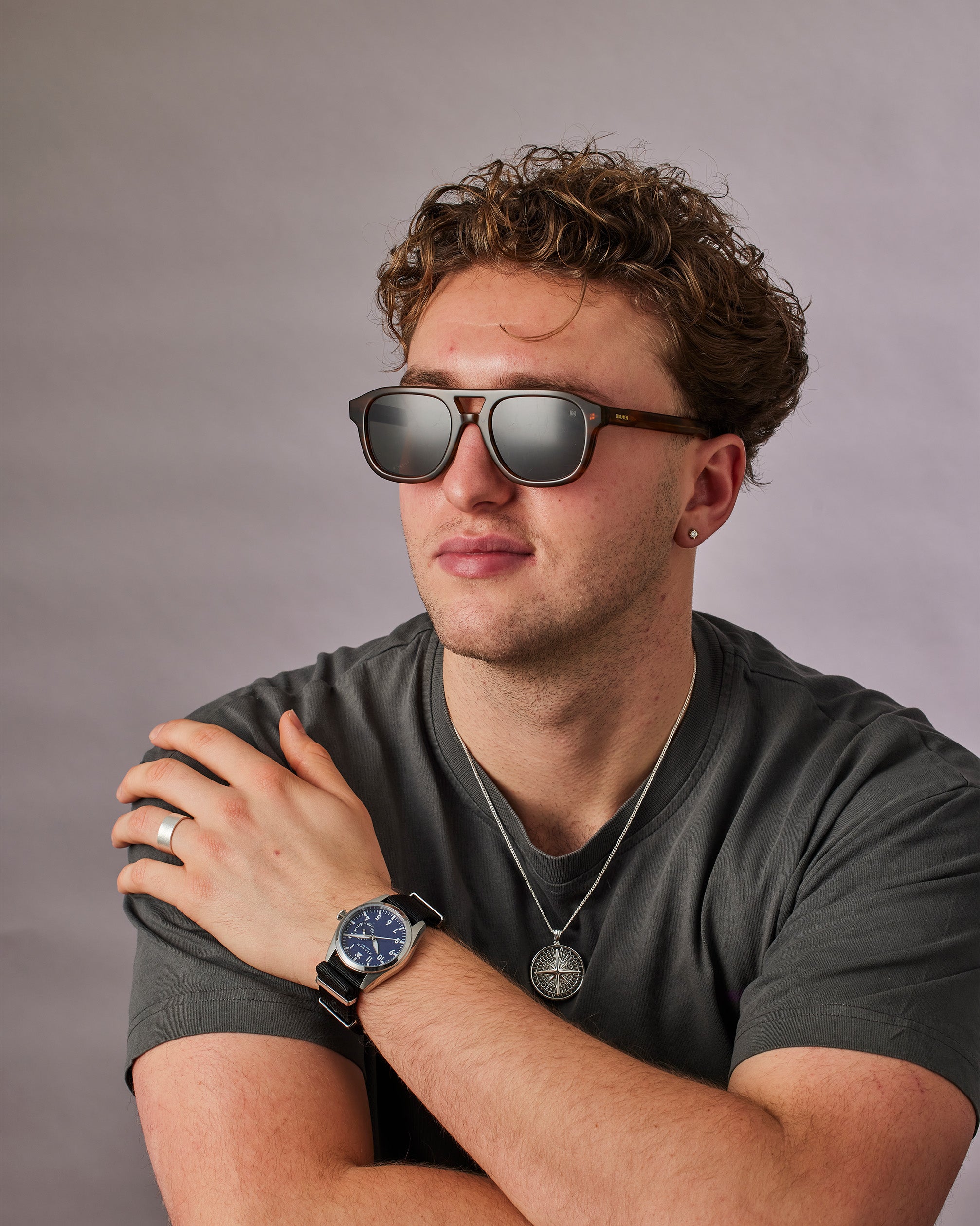 Man wearing sunglasses and a watch with a gray background