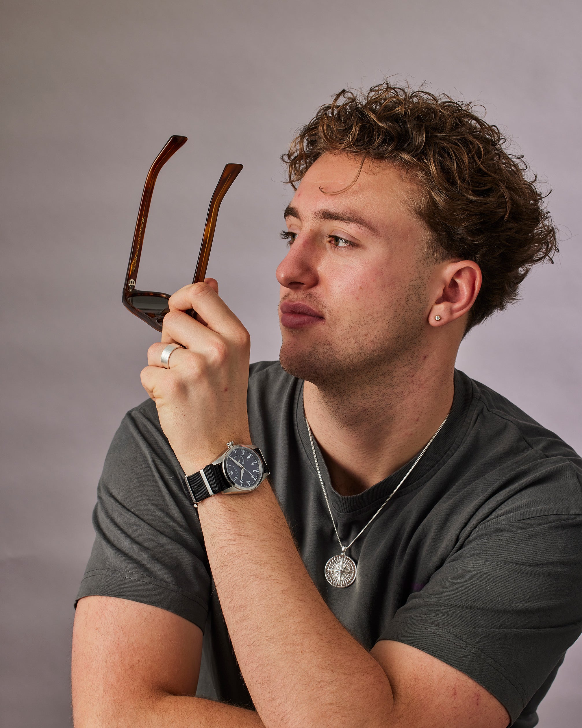 Man holding a pair of glasses with a gray background