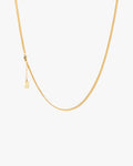 Gold chain necklace on a light grey background