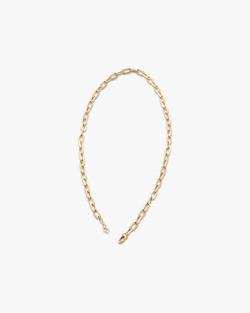 Gold chain necklace on a light grey background